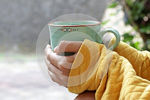 Young woman holding cup of morning coffee or tea in hands outdoors. Still life, self love and care concept.