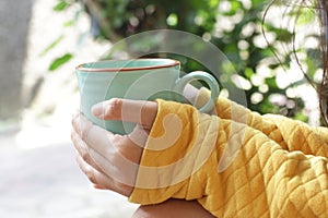 Young woman holding cup of morning coffee or tea in hands outdoors. Still life, self love and care concept.