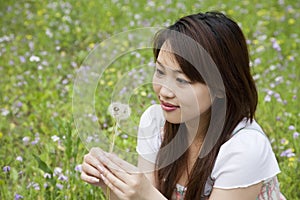 Young woman holding dandelion