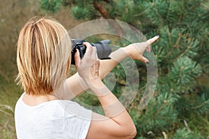 Young woman holding digital camera and taking pictures