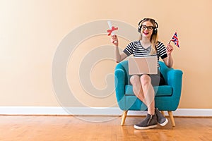 Young woman holding a diploma and UK flag with her laptop