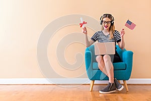 Young woman holding a diploma and USA flag with her laptop