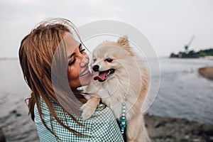 Young woman is holding dog outdoors