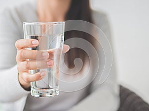 Young woman holding drinking water glass in her hand.
