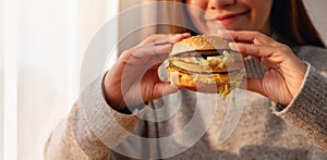 A young woman holding and eating hamburger