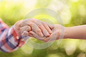 Young woman holding elderly man hand