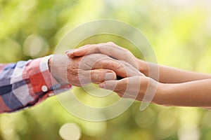 Young woman holding elderly man hand