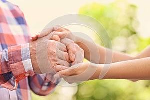 Young woman holding elderly man hands