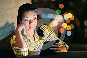 Young Woman Holding Ereader And Reading Ebook At Night photo