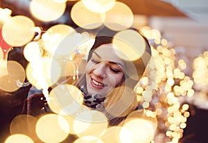 Young woman holding fairy lights in bokeh at winter christmas market