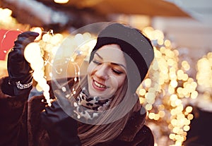 Young woman holding fairy lights at winter christmas market