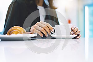 Young woman holding in female hands croissant and drink hot aroma coffee or tea in breakfast time, hipster traveler smile girl