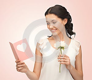 Young woman holding flower and postcard