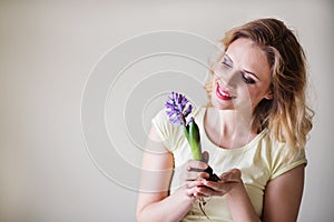 Young woman holding a flower seedling at home.