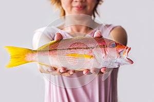 Young woman holding fresh red snapper fish.