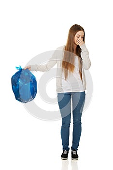 Young woman holding a full garbage bag.