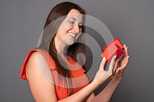 Young woman holding a gift. Beautiful woman opens a box with a gift