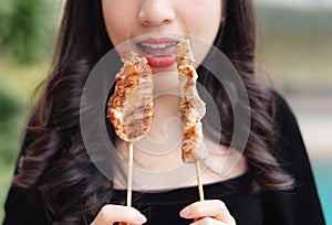 Young woman holding grilled Barbeque, with happy face. Asian street food