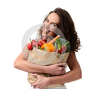 Young woman holding grocery paper shopping bag full of fresh vegetables