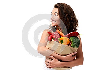 Young woman holding grocery paper shopping bag full of fresh vegetables. Diet healthy eating concept