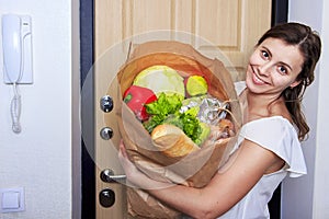 Young woman holding grocery shopping bag with vegetables .Paper packege is full of food.