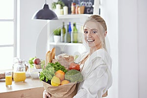 Young woman holding grocery shopping bag with vegetables Standi