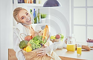 Young woman holding grocery shopping bag with vegetables Standi