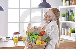 Young woman holding grocery shopping bag with vegetables Standing in the kitchen