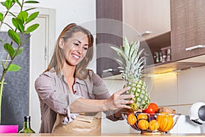 Young woman holding grocery shopping bag with vegetables .Standing in the kitchen. Healthy positive happy woman holding a paper