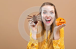 Young woman holding a halloween pumpkin and a spider