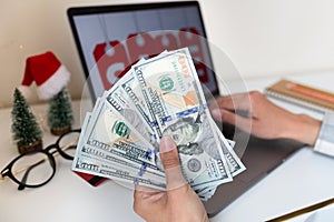 Young woman holding hand cash money one hundred dollars bills, holiday shopping. Person using technology