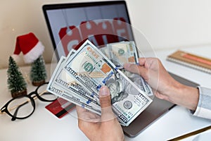 Young woman holding hand cash money one hundred dollars bills, holiday shopping. Person using technology