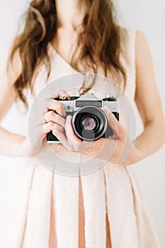 Young woman holding in hands old vintage camera. Girl photographer