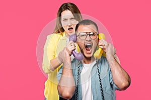 young woman holding handsets and man in eyeglasses yelling isolated