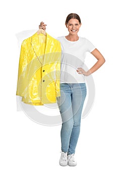 Young woman holding hanger with jacket in bag on white background. Dry-cleaning service