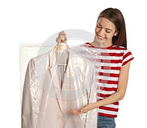 Young woman holding hanger with jacket in plastic bag on background. Dry-cleaning service