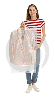 Young woman holding hanger with jacket in plastic bag on background. Dry-cleaning service