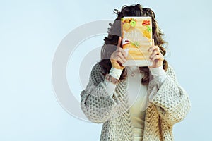 Young woman holding healthy eating book in front of face