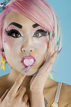 Young woman holding a heart shaped candy on her lips
