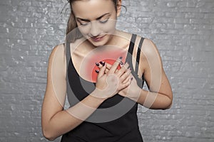 A young woman is holding her chest, Possible heart attack or other heart disease, front view