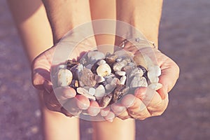 Young woman holding on her hand the beautiful colorful pebbles of Greek beaches