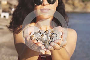 Young woman holding on her hand the beautiful colorful pebbles