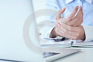 Young woman holding her sore hand on wrist close-up. Pain from using computer. Office syndrome hand pain by occupational