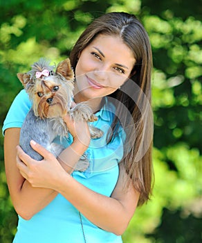 Young woman holding her sweet little puppy - outdoor portrait
