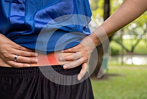 A young woman holding his back in pain in the garden