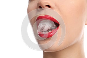 Young woman holding ice cube in mouth on white background