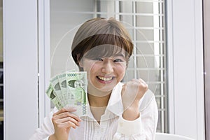 Young woman holding Japanese Yen and Korean Won