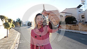 Young woman holding keys while standing outdoor against new house.