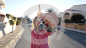 Young woman holding keys while standing outdoor against new house.