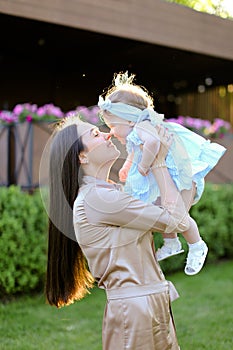 Young woman holding and kissing little daughter.